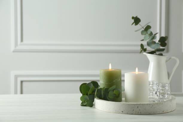 istock Burning candles and branches of eucalyptus on white table indoors, space for text 1464772465