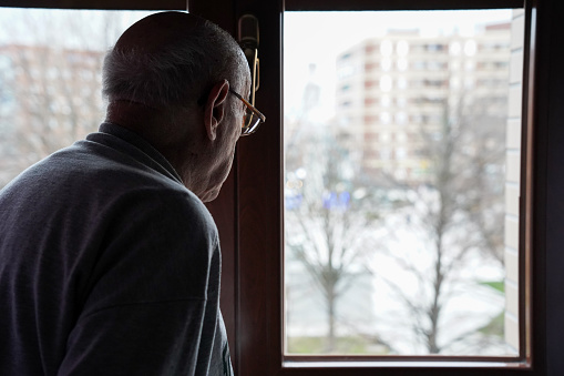 caucasian senior looking at the window. loneliness in elderly