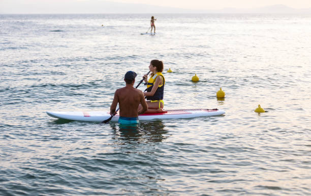 istock Teenage girl learning how to paddle boarding with instructor 1464773933