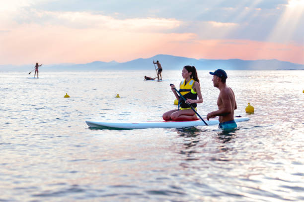istock Teenage girl learning how to paddle boarding with instructor 1464773939