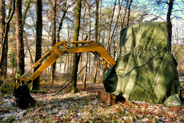 Excavator left in woodland and covered in tarpaulin for snow protection