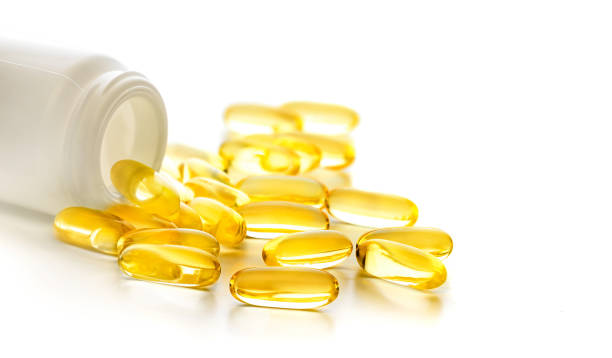 istock Yellow capsules of omega 3 pours from white plastic medicine container 1464777730