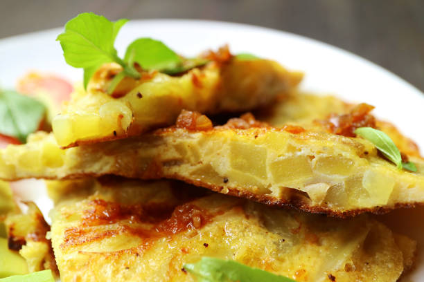 closeup fette di frittata spagnola o tortilla de patatas guarnite con foglie di basilico fresche - tortilla de patatas foto e immagini stock