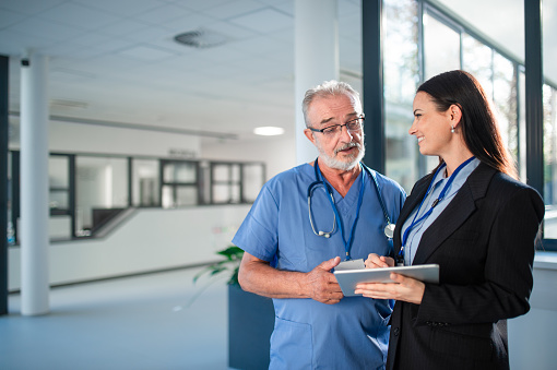 Young business woman shaking hand with elderly doctor in a hospital.
