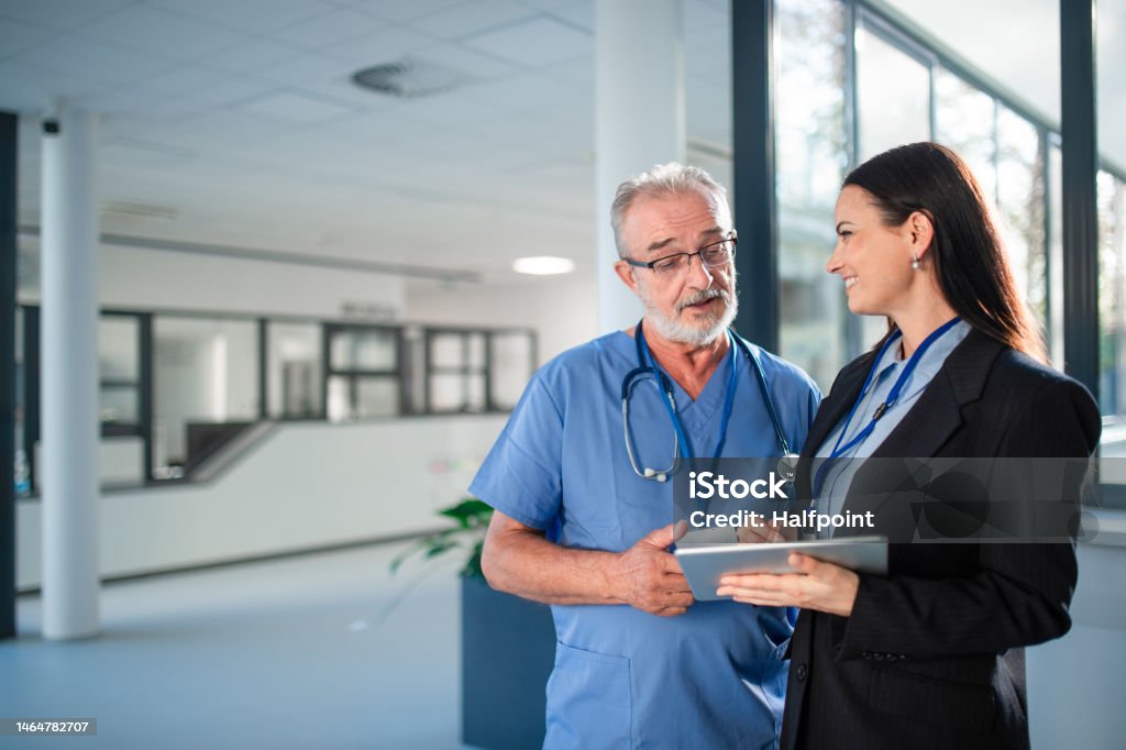 Young business woman shaking hand with elderly doctor. Young business woman shaking hand with elderly doctor in a hospital. Doctor Stock Photo