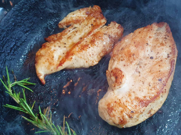 Frying two chicken breast fillets stock photo