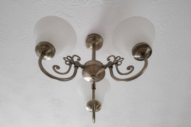 Newly installed vintage-looking ceiling lights located in a show home. One of a pair of lights in a large living room.