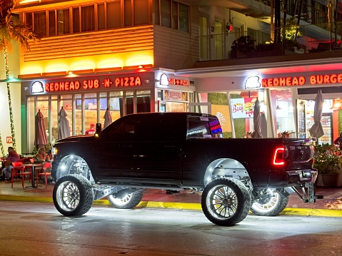 Miami South Beach, FL - USA, February 1, 2023. An illuminated and adorned Ram pickup truck in front of the popular Redhead sub and pizza shop. The being seen crowd with lifted and lit truck along Ocean drive Miami Beach.