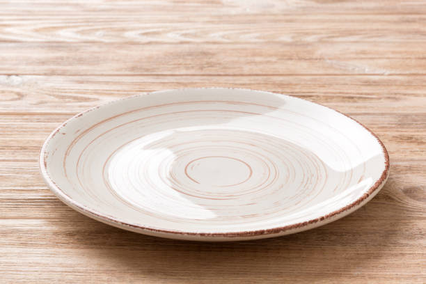 istock Perspective view of empty colorful plate on wooden background. Empty space for your design 1464787064