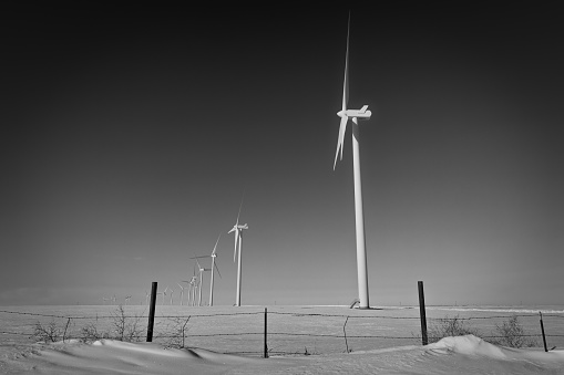 A wind farm operates past a barbed wire fence near rural Limon, Colorado.