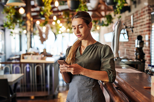 Phone, bartender or small business woman for communication, networking or online blog content reading. Research, internet or employee on smartphone for search, website or social media review in cafe