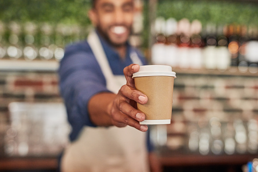 Waiter, coffee cup and man giving drinks in cafe, shop or restaurant. Closeup barista, takeaway beverage and tea latte for hospitality service, fast food worker or catering startup in cafeteria lunch