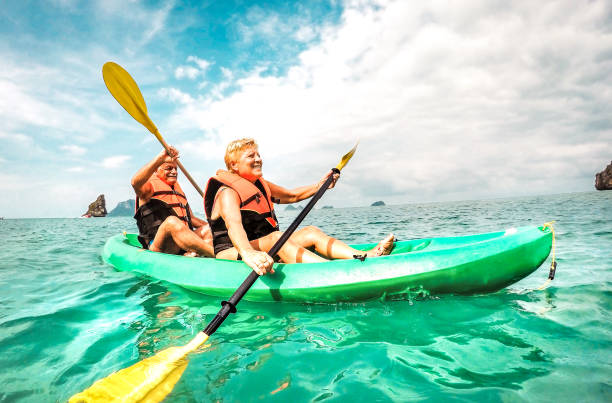 coppia di pensionati felici che si godono il momento di viaggio pagaiando in kayak al parco marino di angthong a ko samui in tailandia - concetto di anziani attivi intorno alle meraviglie della natura del mondo - tono filtrato vivido e brillante - canoeing canoe senior adult couple foto e immagini stock