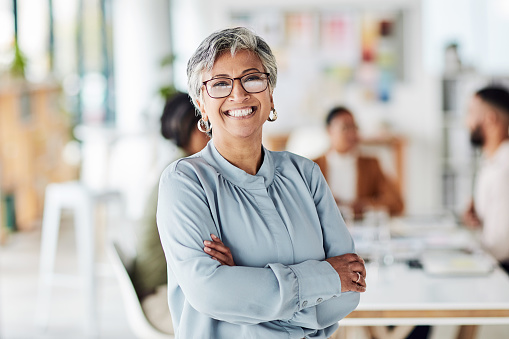 Leadership, portrait and business woman in the office with crossed arms, smile and confidence. Happy, leader and professional senior female employee or company manager standing in modern workplace.