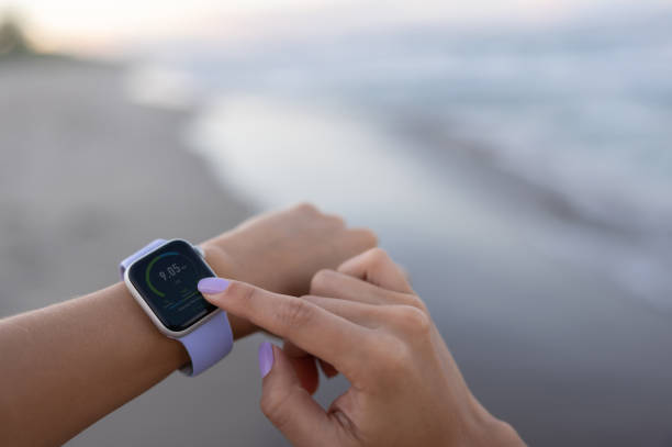 istock Close-up on a woman using a smart watch while exercising at the beach 1464792301