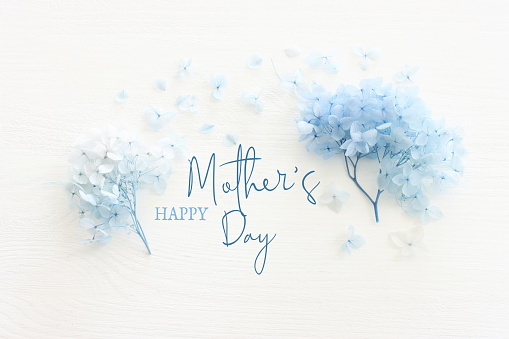 mother's day concept with blue flowers over white wooden background