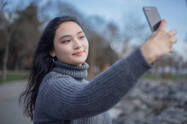 istock Young asian girl standing and taking selfie while walking 1464797477