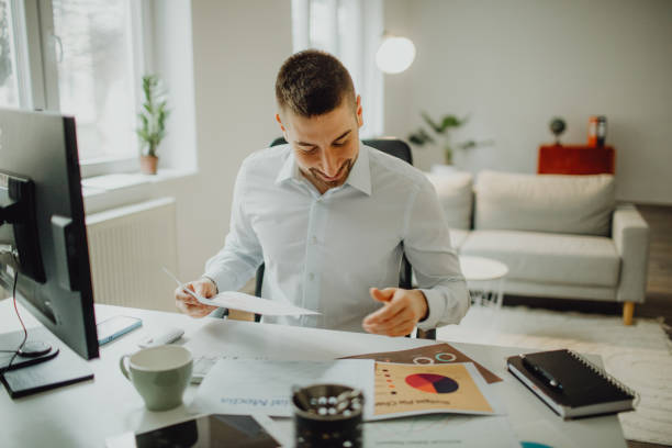Smiling young businessman working on strategy and paperwork in his office stock photo