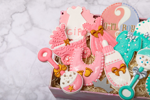 A set of baby shower cookies in a gift box on a marble background. Holiday concept. Baby party. View from above. Flat lay.