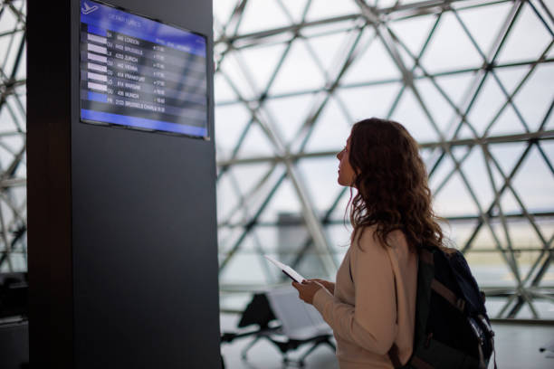 Female teenage girl checking the arrival departure board at the airport stock photo