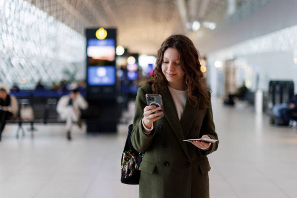 istock Smiling young woman using mobile phone at airport 1464801027