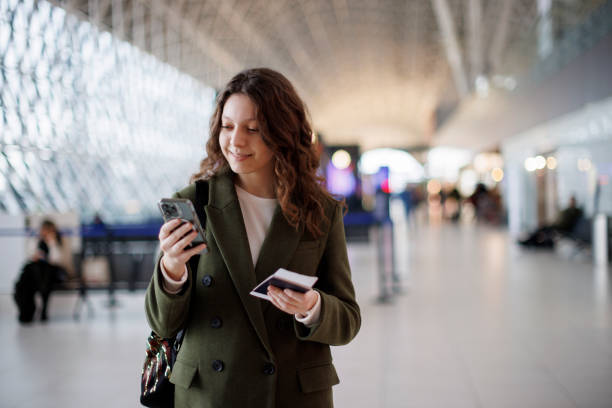 istock Smiling young woman with backpack checking her boarding schedule at the airport 1464801085