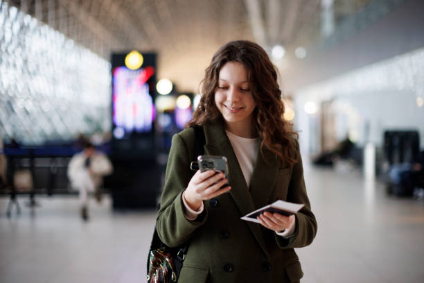 Young woman with backpack checking her boarding schedule at the airport stock photo
