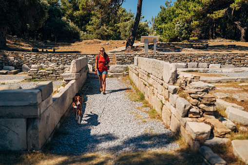 A female tourist and her tricolor dog visit an archaeological site on Thassos island