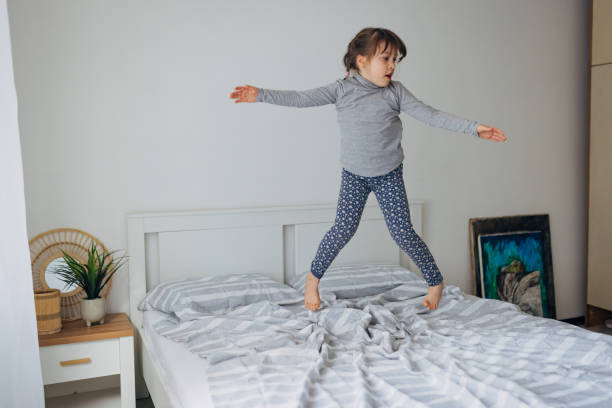 istock Happy little girl having fun while jumping on a bed in bedroom 1464802807