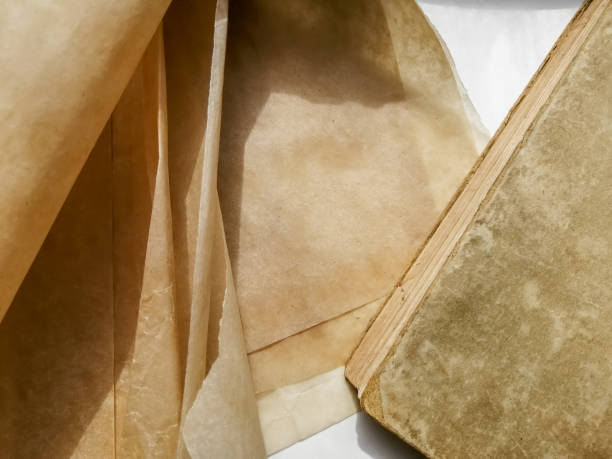 istock Old parchment next to an old book. Ancient manuscripts on a white table. 1464807850
