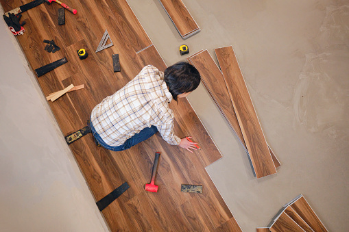 A woman installing laminate flooring in her home.