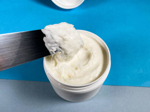 istock white jar with cream and spatula close up on blue 1464815645