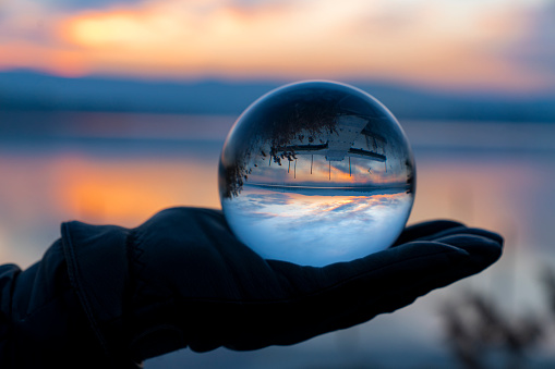 Man Holding Crystal Ball With Reflection Of Lake