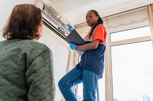 black female  Service worker explaining female customer how to  use  air conditioner