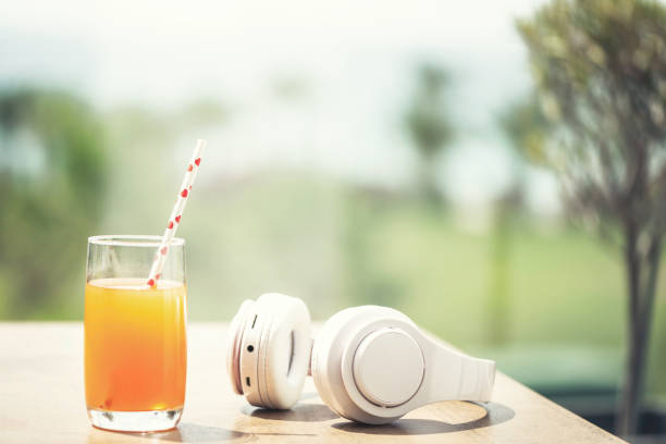 Headphones, orange juice on the table in the palm tree forest. Summer vocation. Copy space. Concept Headphones, orange juice on the table in the palm tree forest. Summer vocation. Copy space. Concept tropic of capricorn stock pictures, royalty-free photos & images