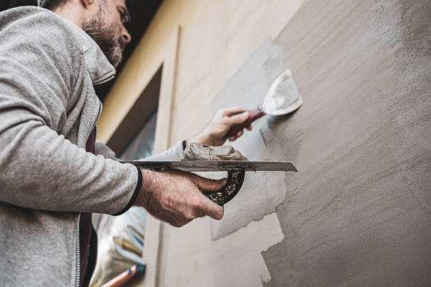 ristrutturazione della facciata dell'edificio - industria delle costruzioni. operaio che intonaca le pareti esterne di una casa. - plaster plasterer wall repairing foto e immagini stock