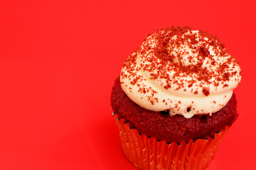 Classic red velvet cupcake with cream cheese frosting isolated on white background.