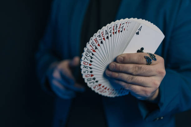 immagine ravvicinata delle mani di un giovane mago al buio con un mazzo di carte a forma di ventaglio che mostra la parte anteriore del mazzo. - fan deck foto e immagini stock