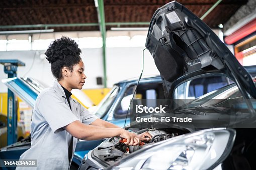 istock Auto mechanic woman repairing the car engine on the repair shop 1464834428