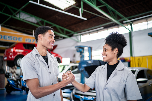 Auto mechanics doing a handshake celebrating on the repair shop