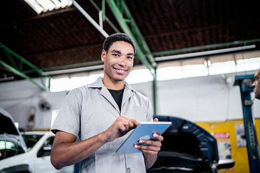 Portrait of an auto mechanic man using a digital tablet on the repair shop