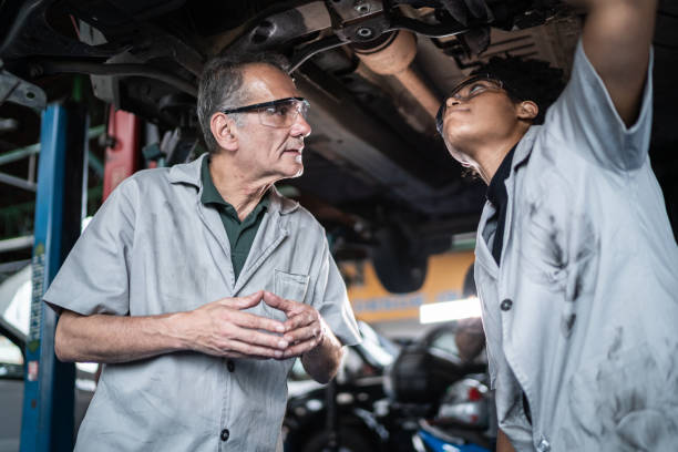 istock Auto mechanic man teaching his assistant on the repair shop 1464835532