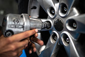 Close-up of a human hand screwing a wheel on a repair shop