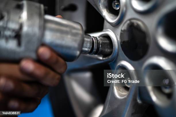 Closeup Of A Human Hand Screwing A Wheel On A Repair Shop Stock Photo - Download Image Now