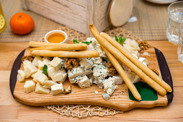 istock Cheese platter with gorgonzola, blue cheese, walnuts and honey. Few bread sticks. 1464845641