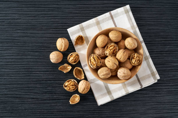 istock walnuts in wooden bowl on black table with copy space. Top view 1464850343