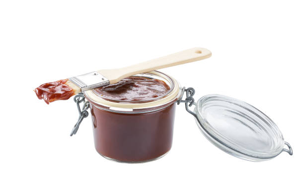 istock Barbecue sauce in a jar with barbecue brush isolated on a white background. 1464850434