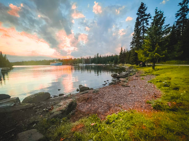 Spectacular Sunset Views of Lake Superior and Rock Harbor from the Coast of Isle Royale National Park Looking out over the shoreline and pure waters of Lake Superior from the coast of Rock Harbor on the Northern island of Isle Royale. The coastline of this island is covered in green evergreen trees and moored ferries and sailboats dot the shoreline. The visitors center can be seen in the distance. Located in the Upper Peninsula of Michigan. lakeshore stock pictures, royalty-free photos & images