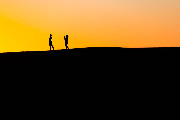 istock Sunset at Maspalomas Dunes - people shadows at clear sky at sunset 1464854584