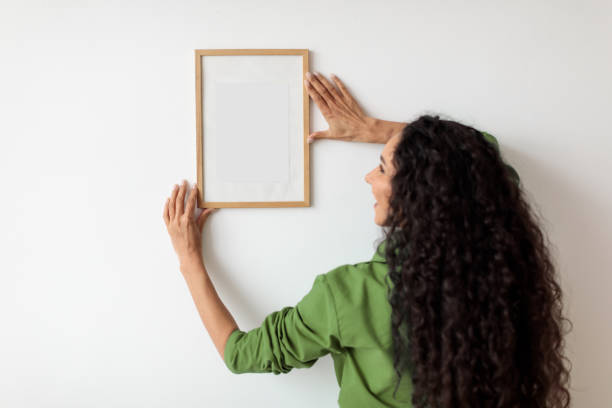 istock Female Hanging Empty Picture In Frame On White Wall Indoors 1464865625